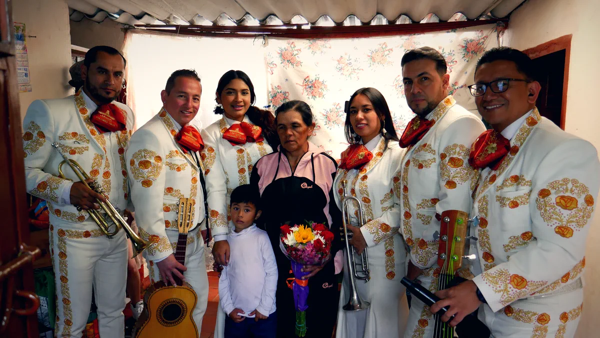 Mariachi Colombia Show cantando dentro de una casa a una señora que recibe flores