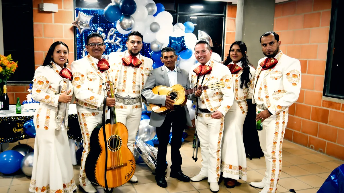 Mariachi Colombia Show con el homenajeado frente a un arco de globos azules y plateados